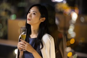 夜景をバックにカクテルを飲む女性