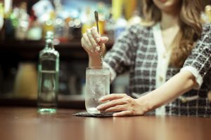 カウンターバーでお酒を提供する若い女性